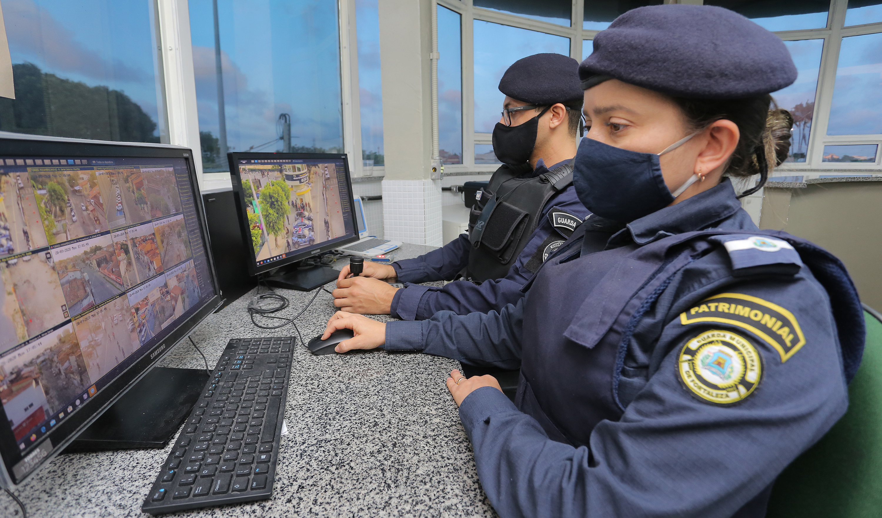 duas guardas municipais de máscara olham os monitores dentro da célula proteção comunitária